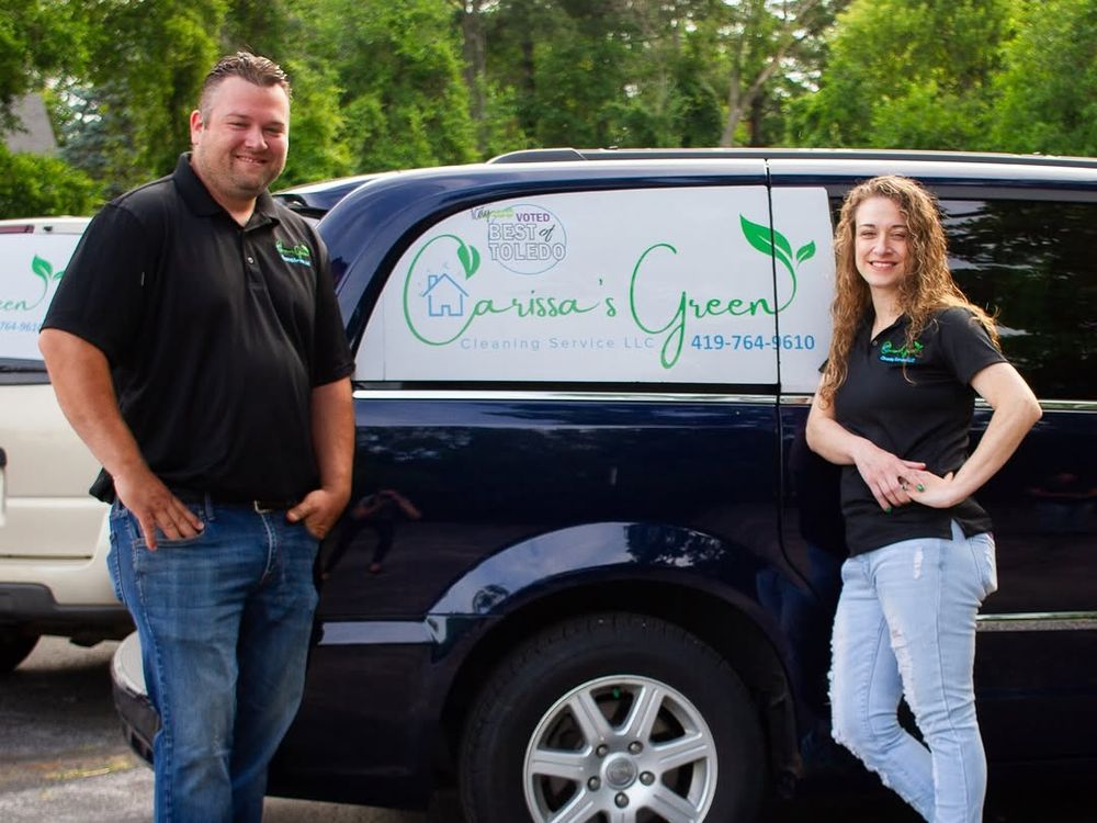 Two members of the team in black polo shirts standing beside a navy van lettered Carissa's Green Cleaning Service, with a Best of Toledo badge on the door.